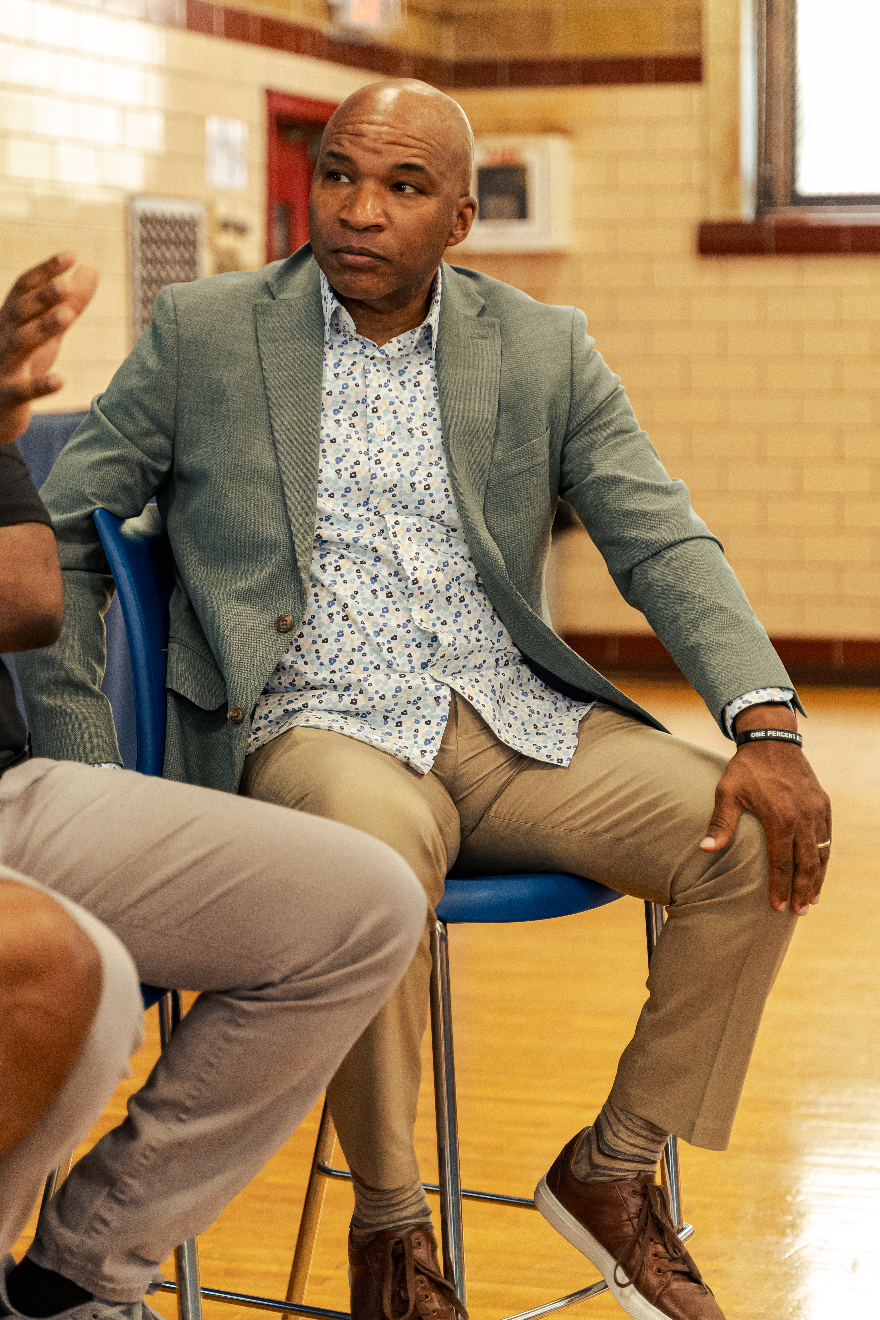 Chris Rivers seated in a gymnasium, mid-conversation, in a candid coaching moment.